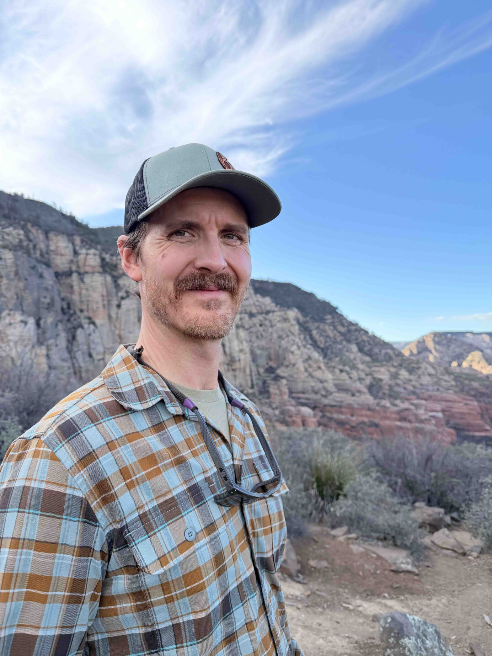 A man with a hat and a mountain range behind him