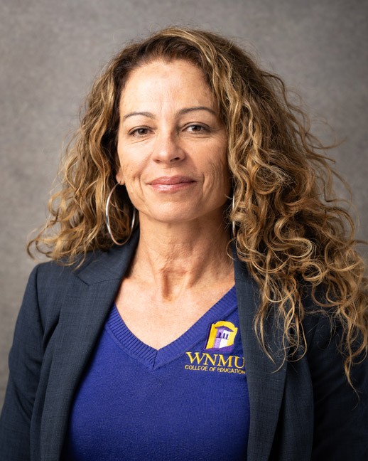 woman with long curly hair and a WNMU Scrubs shirt