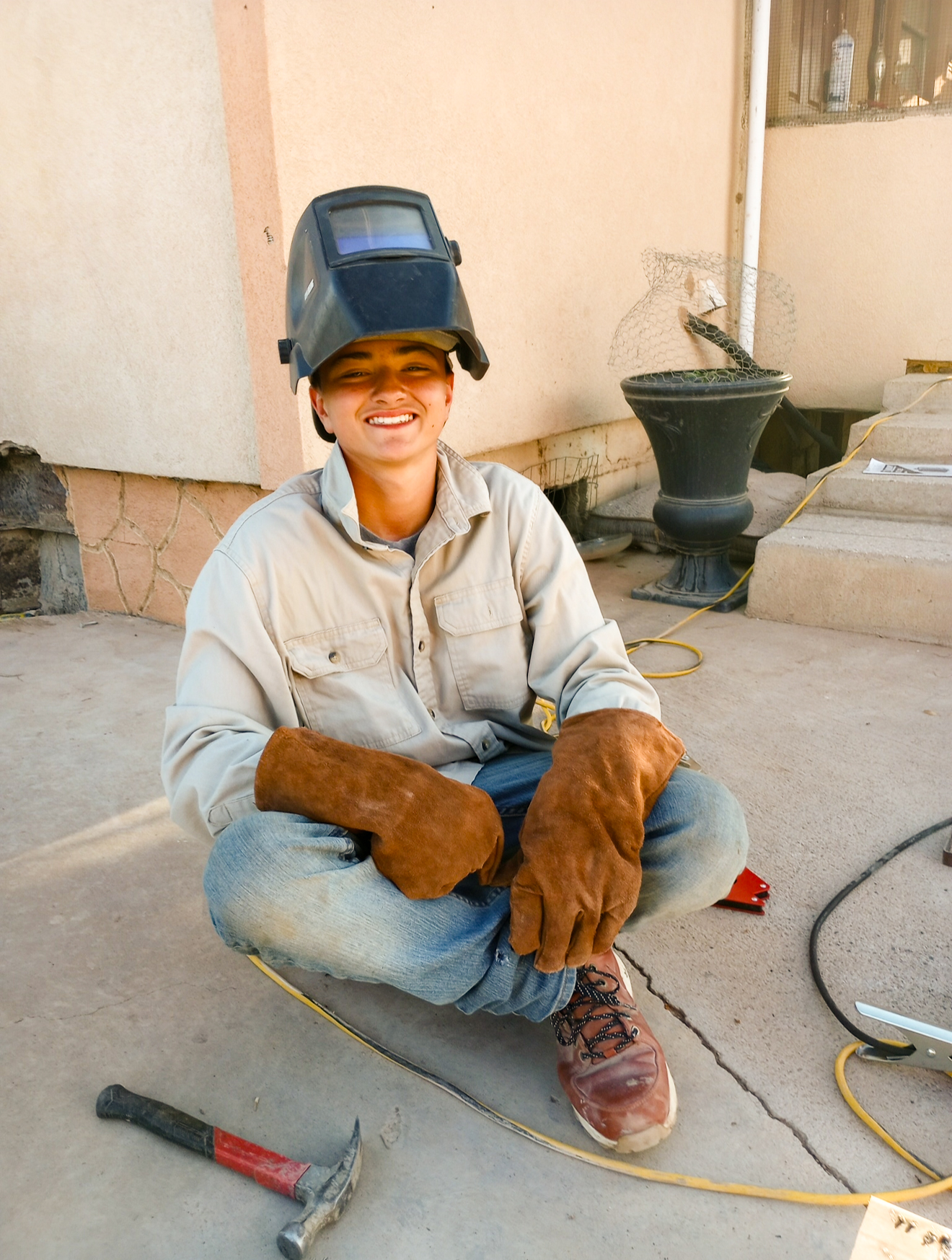 a 16 year old boy in a welding cap and outfit, demonstrating his welding skills.