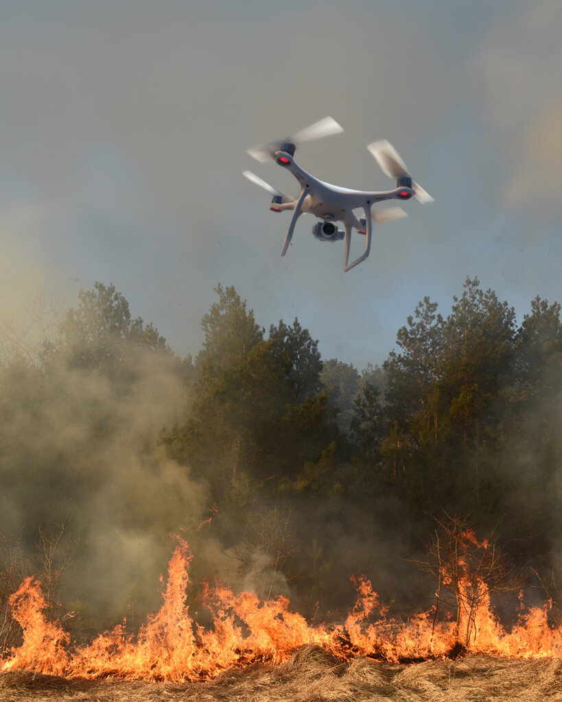 Image of large drone hovering over a wildfire